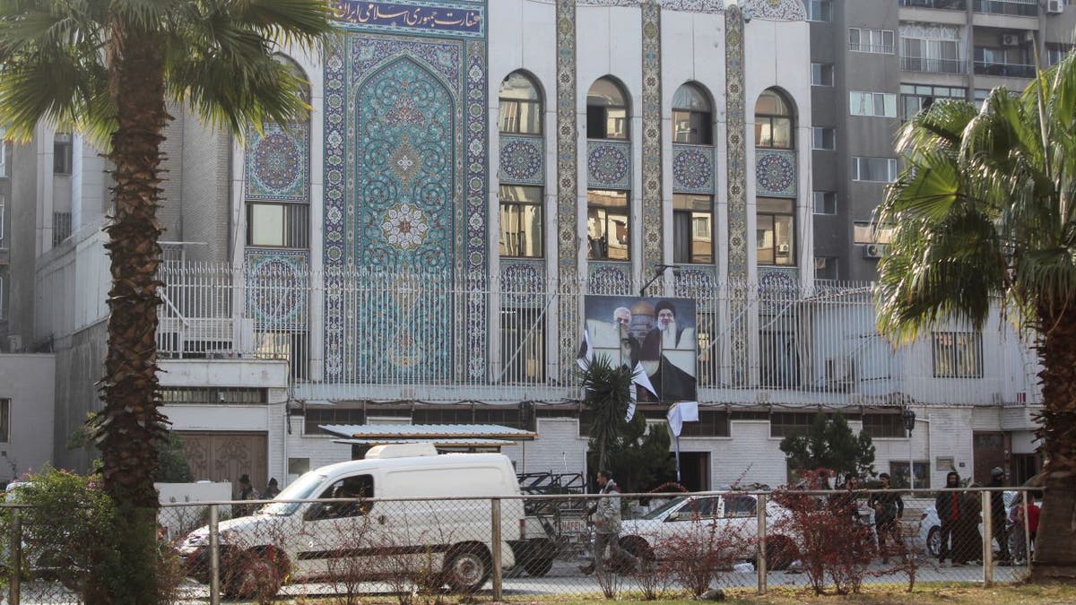 Rebel fighters stand near the Iranian embassy with a torn poster of Hezbollah leader Sayyed Hassan Nasrallah and Iran commander Qassem Soleimani after Syrian rebels announced that they have ousted President Bashar al-Assad, in Damascus, Dec. 8, 2024.