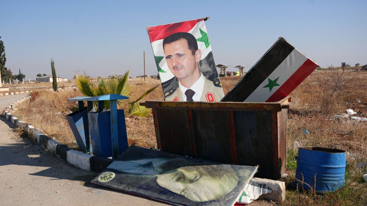 The entrance of the Kweyris military airfield in the eastern part of Aleppo province on Dec. 3, 2024, where a portrait of  Syria's President Bashar al-Assad and a national flag have been thrown in the garbage.