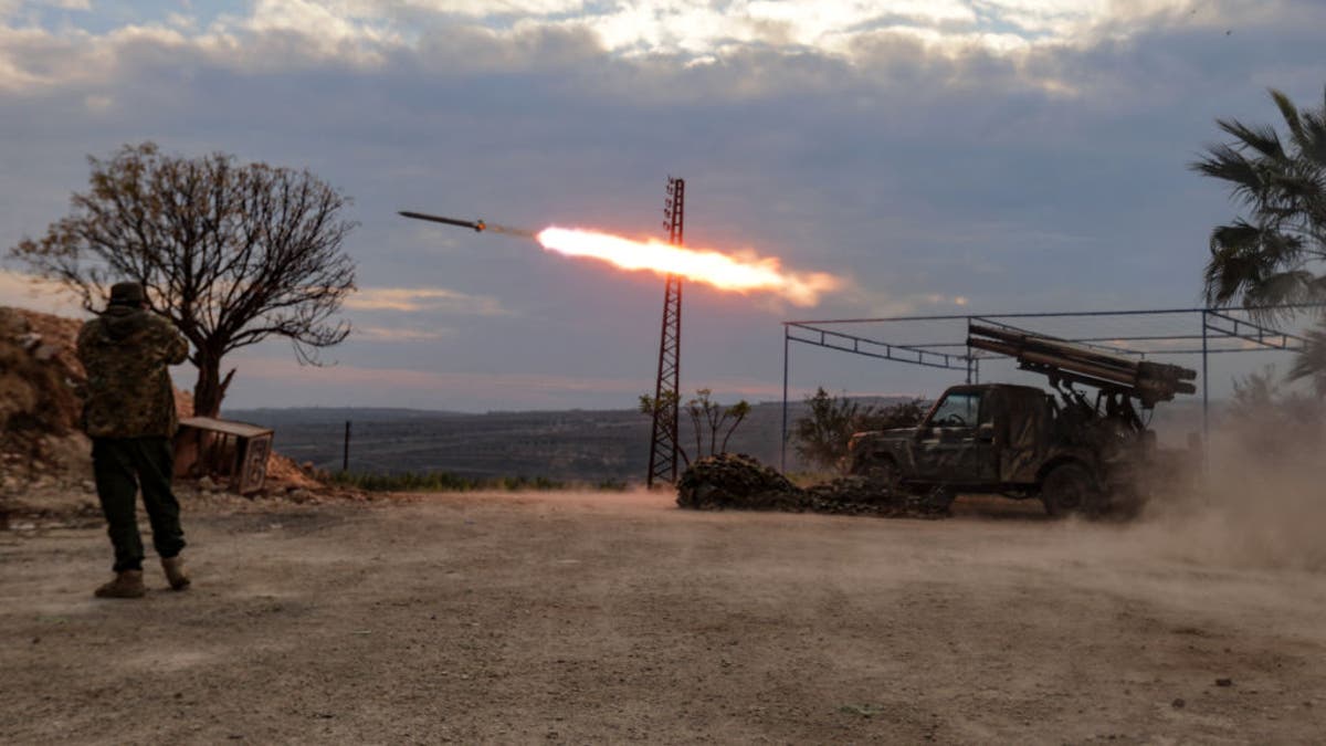 An anti-government fighter covers his ears as a multi-barrel rocket launcher fires against regime forces in the northern outskirts of Syria's west-central city of Hama on Dec. 4, 2024.