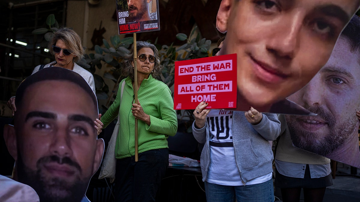 Demonstrators hold photos depicting the faces of Israeli hostages