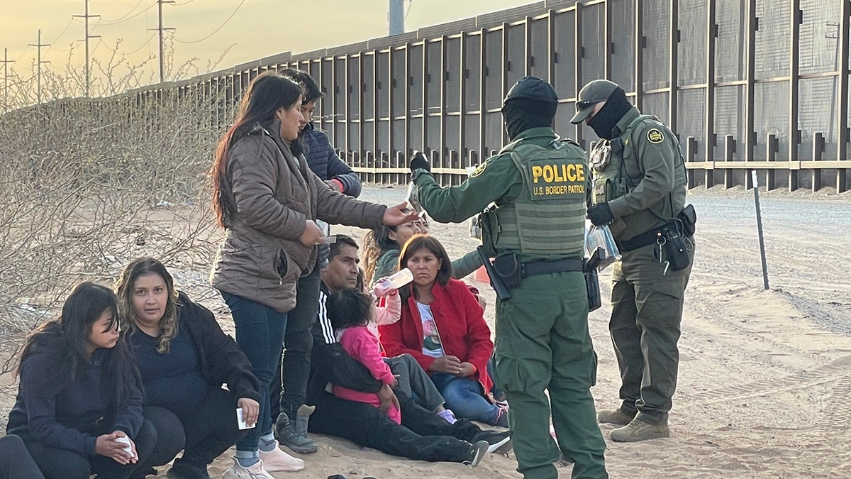 uniformed immigration officers with migrants at border