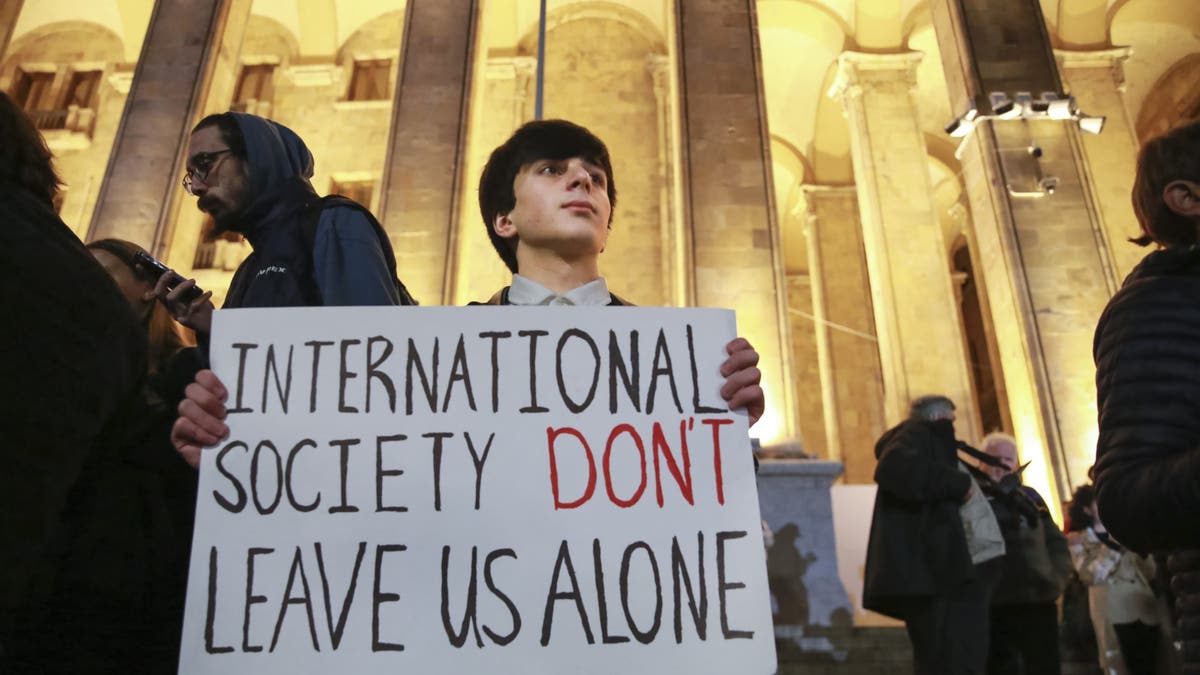 A young demonstrator holds a poster during an opposition protest against the results of the parliamentary election in Tbilisi, Georgia, on Monday, Oct. 28, 2024.