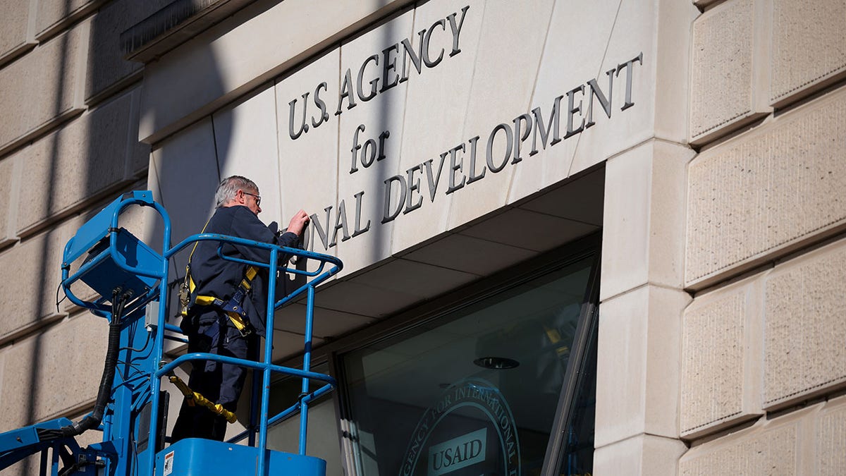  A worker removes the U.S. Agency for International Development sign on their headquarters on Feb. 7, 2025 in Washington, D.C.