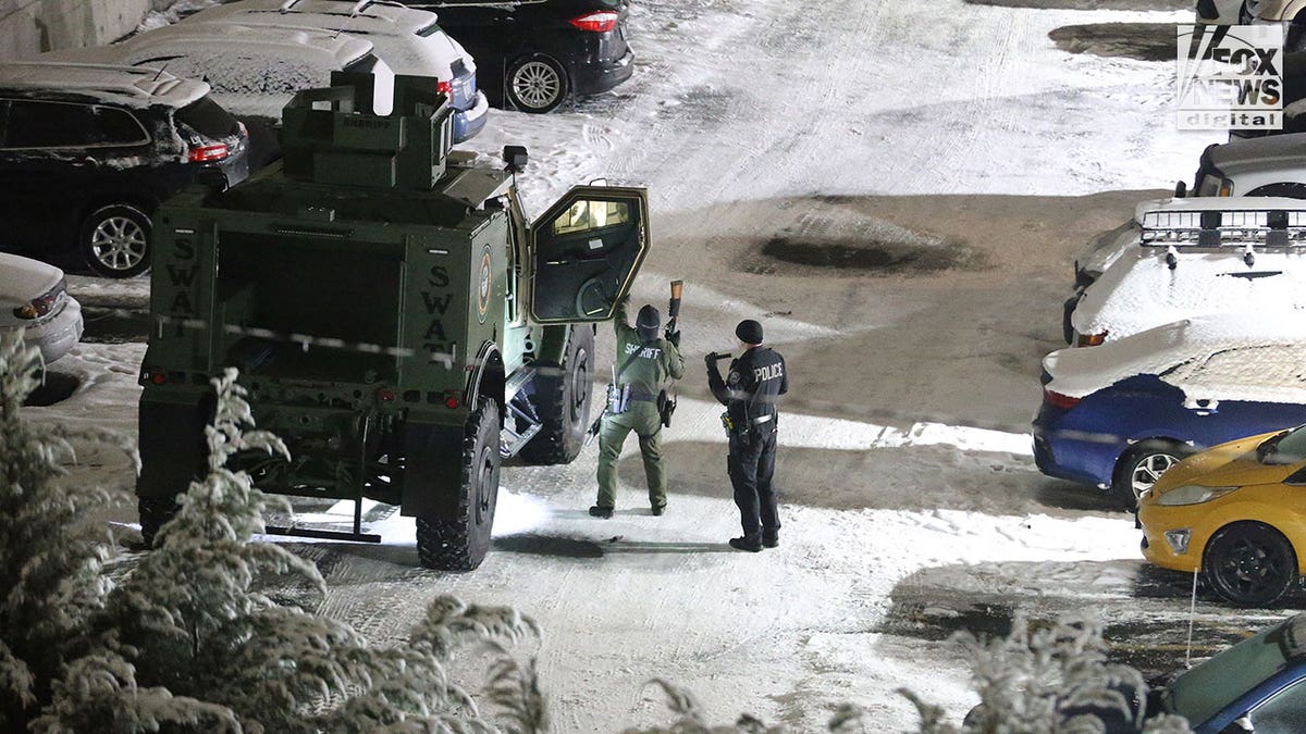 Police walk around in the snow during early morning hours