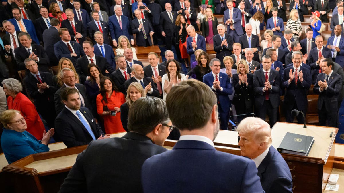 Republican lawmakers applaud as President Donald Trump shakes hands with House Speaker Mike Johnson and Vice President JD Vance before his address at the Capitol on March 4, 2025.