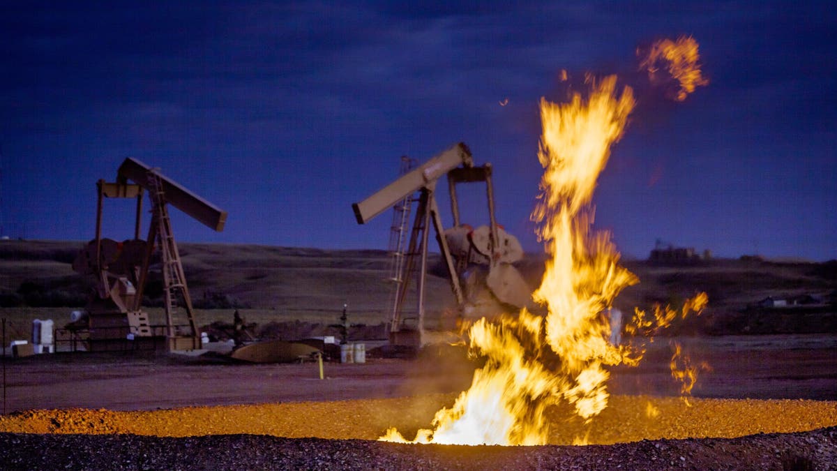 Flames rise up from a flaring pit near a well in the Bakken Oil Field