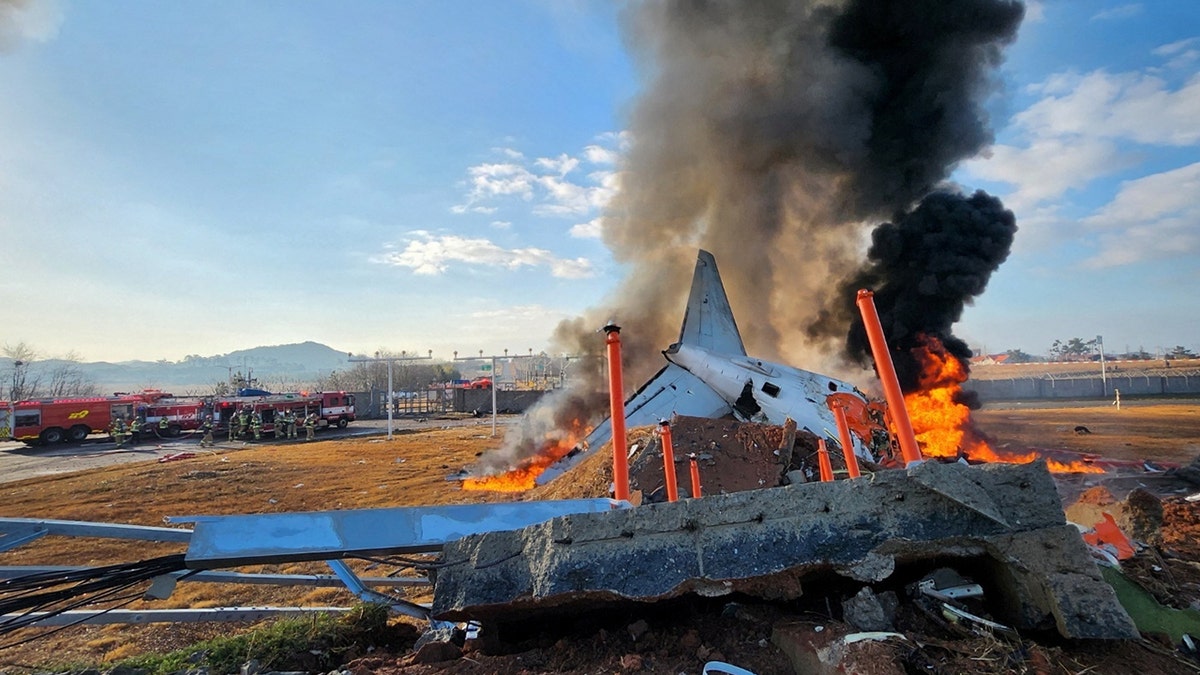 Firefighters carry out extinguishing operations on an aircraft which drove off runaway at Muan International Airport in Muan