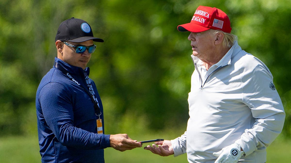 Waltine Nauta, left, takes a phone from Former President Donald Trump