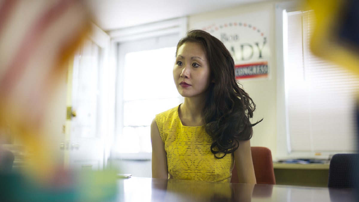 Liny Li in yellow dress at desk