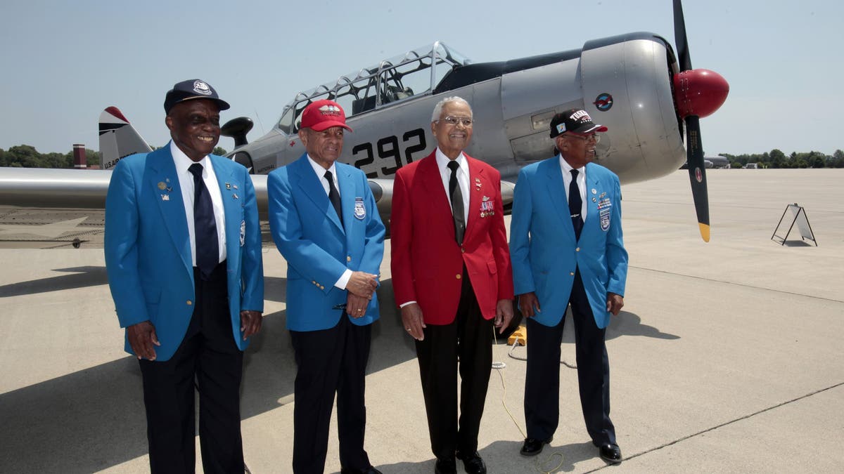 Tuskegee Airmen on tarmac by vintage plane