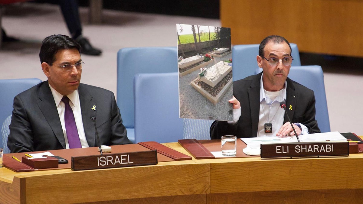 Eli Sharabi shows a photo of his wife and daughters' graves to the UN Security Council.