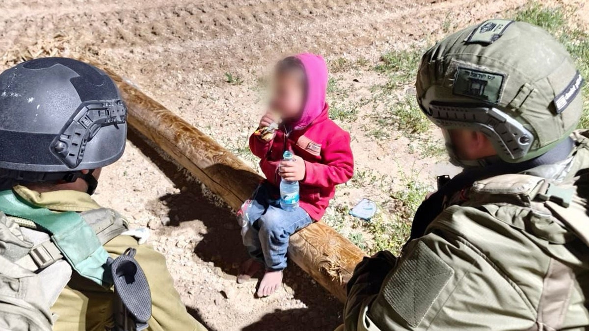 Israeli soldiers speak to a Palestinian child