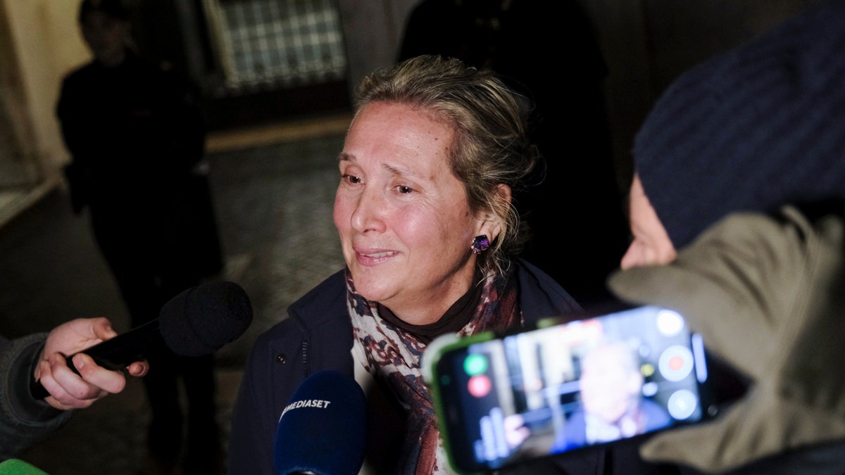 Elisabetta Vernoni, mother of Cecilia Sala, cries as someone holds a microphone to her face and another person records her on a smartphone.