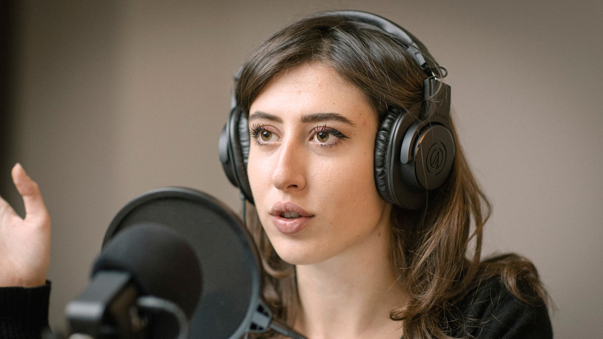 Italian journalist Cecilia Sala wears headphones and gestures as she speaks into a microphone.