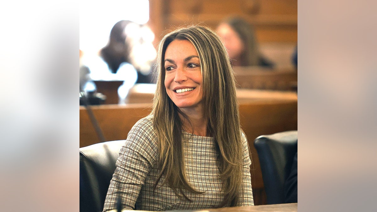 Karen Read smiling wearing a striped sweater in a court room.