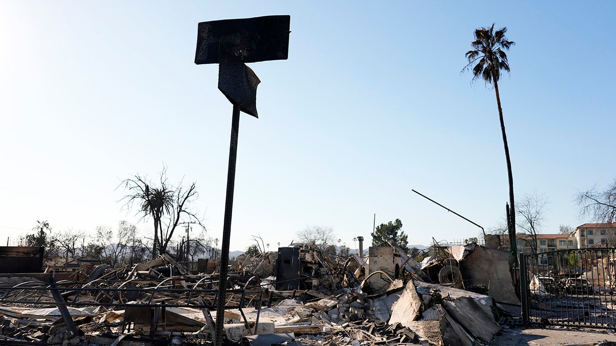 Charred street signs stand near a destroyed Lake Avenue structure after the Eaton Fire