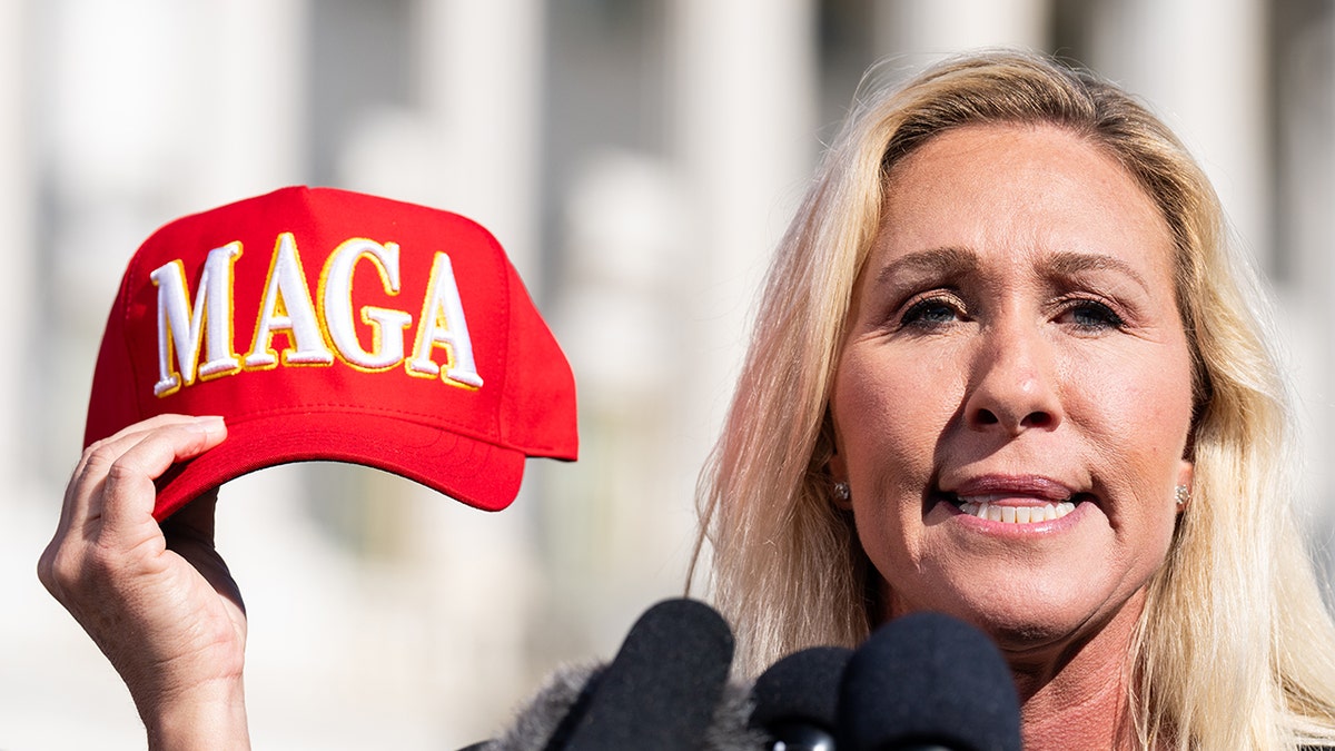 Rep. Marjorie Taylor Greene holding a MAGA hat