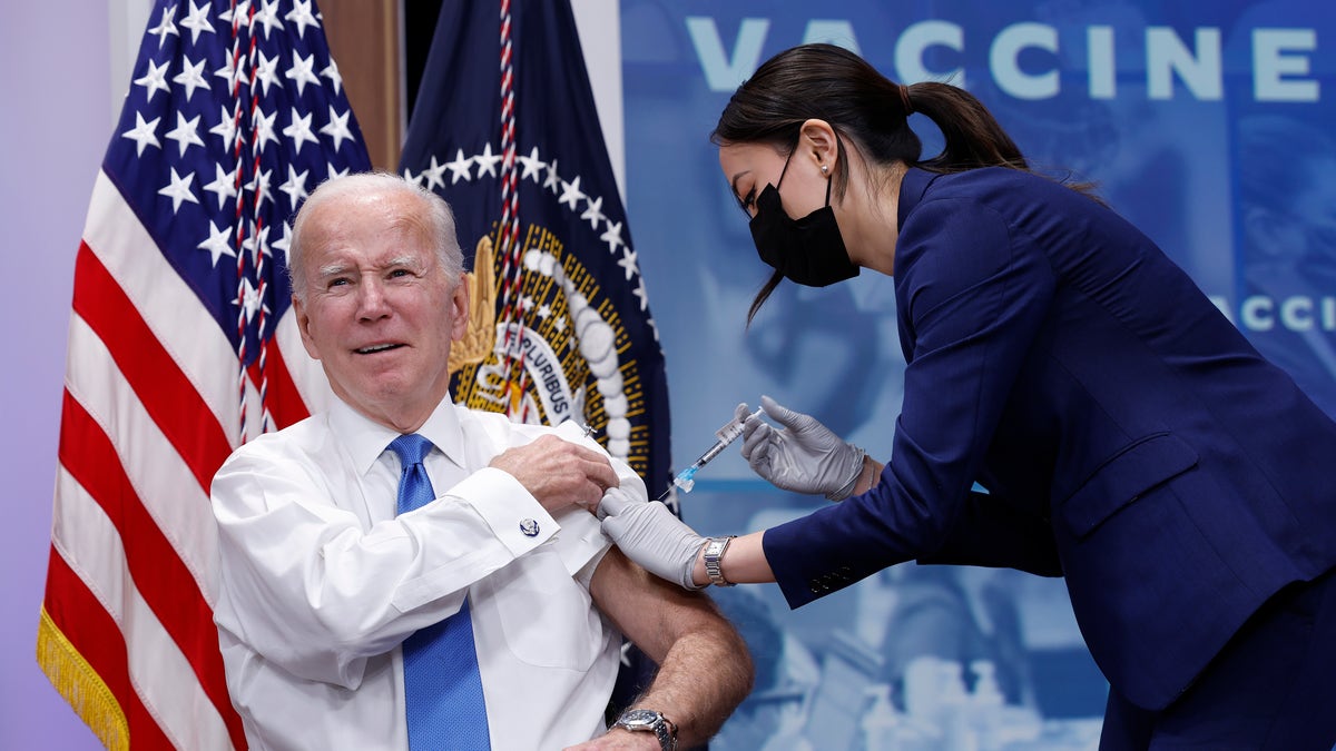 President Joe Biden getting COVID shot in front of flags