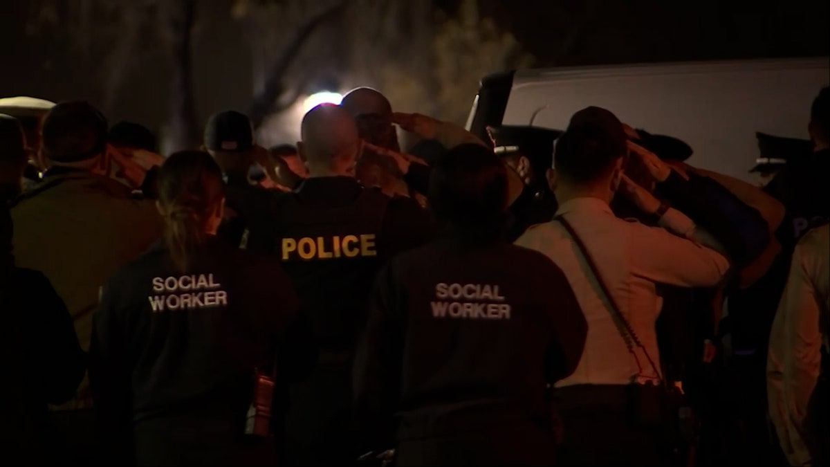 North Las Vegas Police Department (NLVPD) officers salute as two officers escort a van in procession for a slain officer.