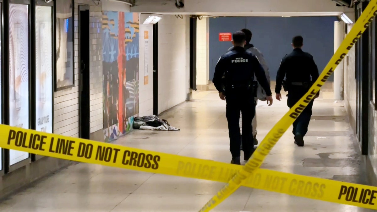 MTA police walk through Penn Station behind caution tape.