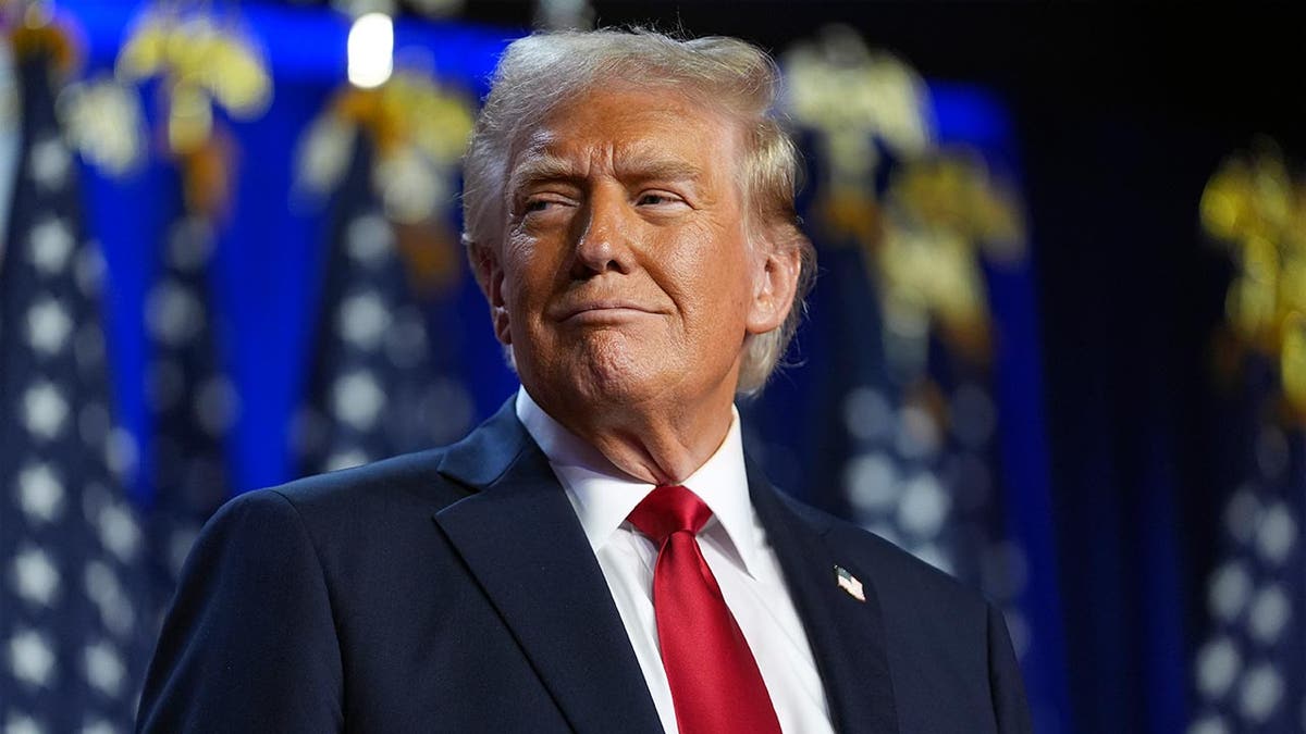 Donald Trump smiles in a navy suit and red tie