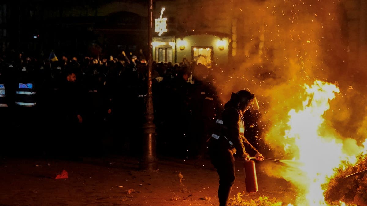 A police officer puts out a fire started by Georgescu supporters