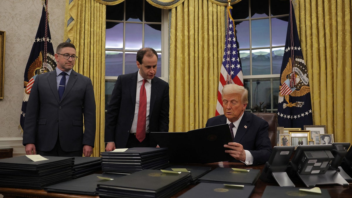 Donald Trump signing pardons at desk in Oval Office