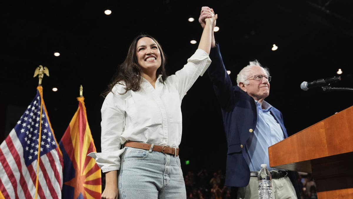 Sen. Bernie Sanders, I-Vt., and Rep. Alexandria Ocasio-Cortez, D-N.Y., greet the crowd together during a "Fighting Oligarchy" tour event at Arizona State University, Thursday, March 20, 2025, in Tempe, Ariz. (AP Photo/Ross D. Franklin)