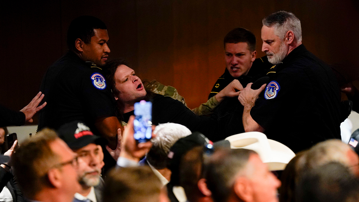 Protester being taken out of hearing by police