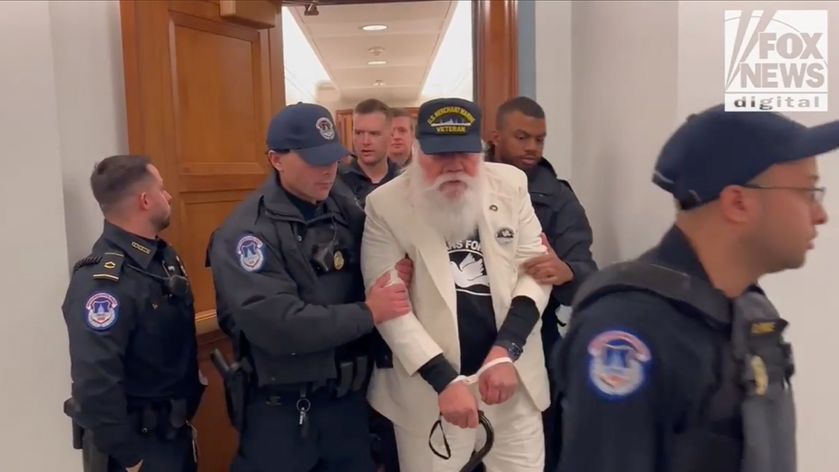 Protester being led out of hearing