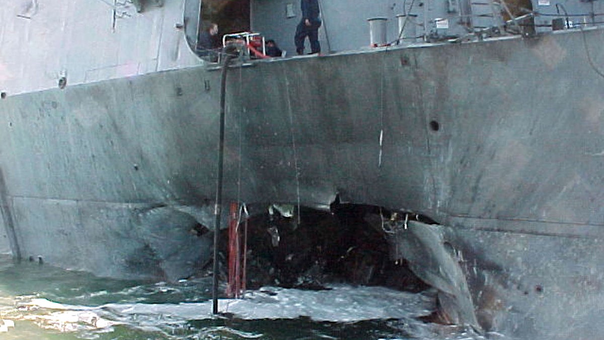 A gaping hole mars the port side of the Arleigh Burke class guided missile destroyer USS Cole