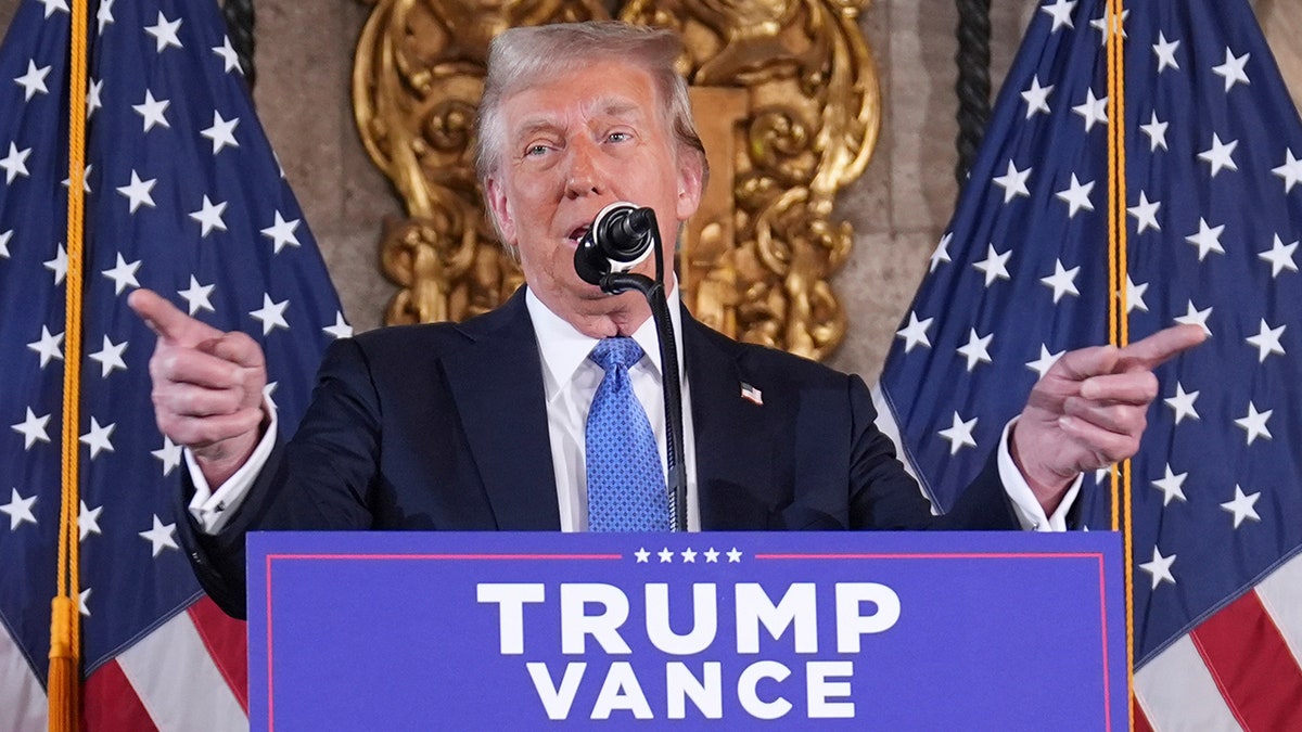 Donald Trump at lectern behind microphone pointing with both hands