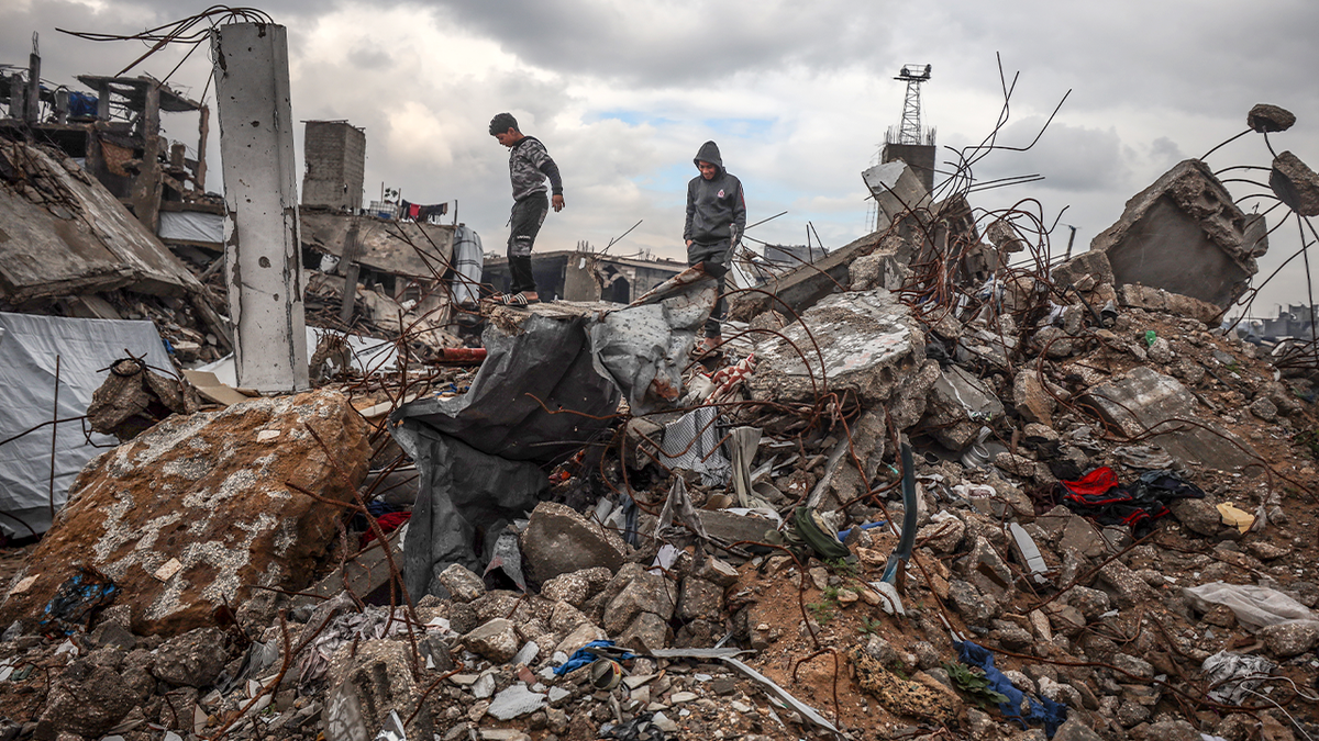 Palestinians walk through the destruction caused by the Israeli air and ground offensive in Jabalia refugee camp in the northern Gaza Strip on February 12, 2025, on a rainy day