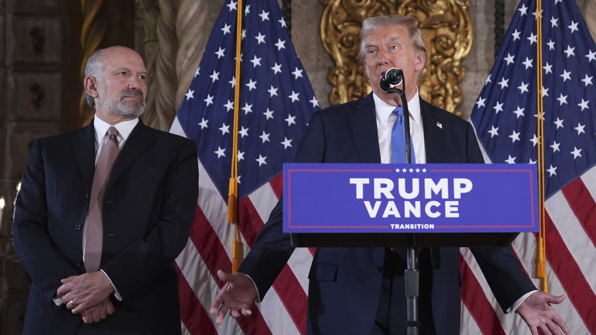 President-elect Donald Trump speaks during a news conference at Mar-a-Lago, Monday, Dec. 16, 2024, in Palm Beach, Fla., as Commerce Secretary nominee Howard Lutnick listens. (AP Photo/Evan Vucci)