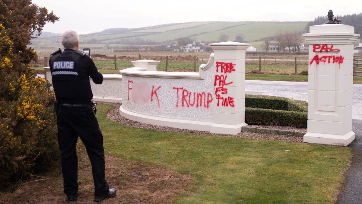 A police officer inspects damage to President Trump's golf resort in Scotland