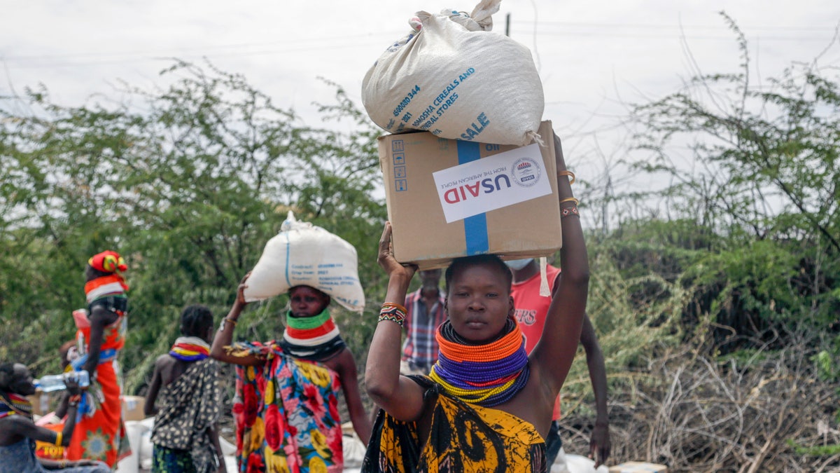 Locals residents carry a boxes and sacks of food distributed by the United States Agency for International Development (USAID), in Kachoda, Turkana area, northern Kenya, Saturday, July 23, 2022