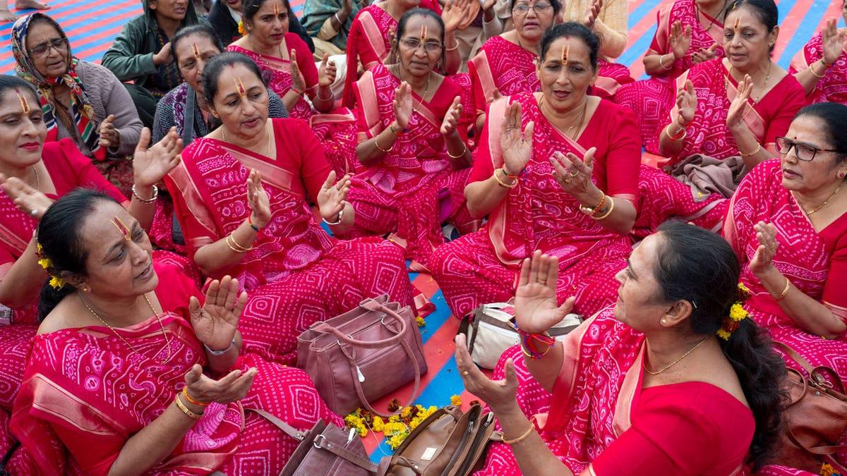 Hindu women devotees dressed in pink sing hymns.