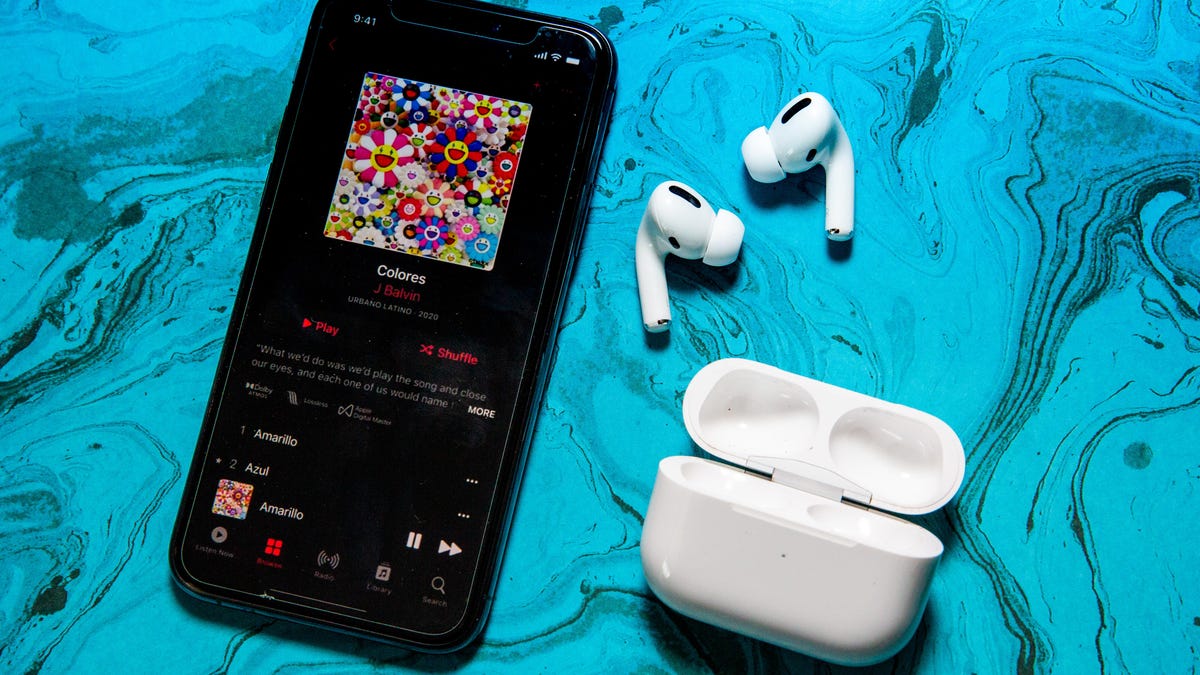 An iPhone with Apple Music on the screen and a pair of AirPods Pro against a teal background