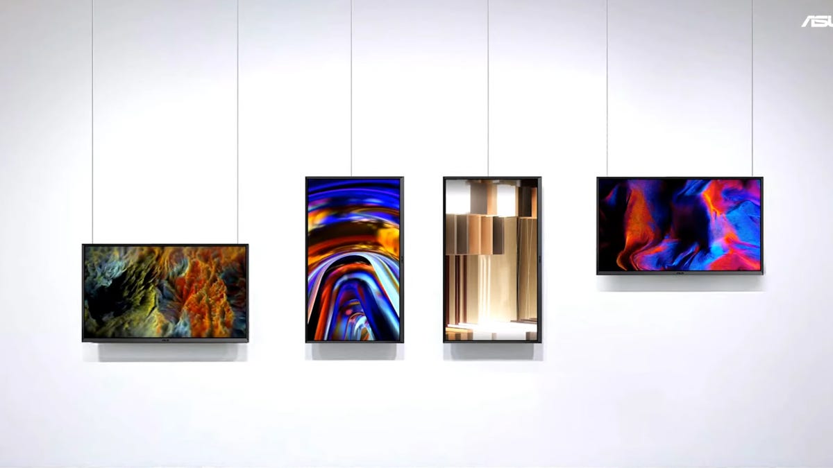 Several ProArt Display OLED PA32DCM monitors mounted on a white wall in landscape and portrait orientations