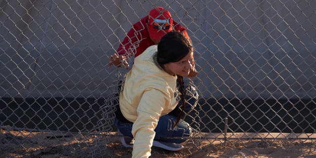 Two people illegally cross into the U.S. through a broken fence in El Paso, Texas, on Dec. 22, 2022. 