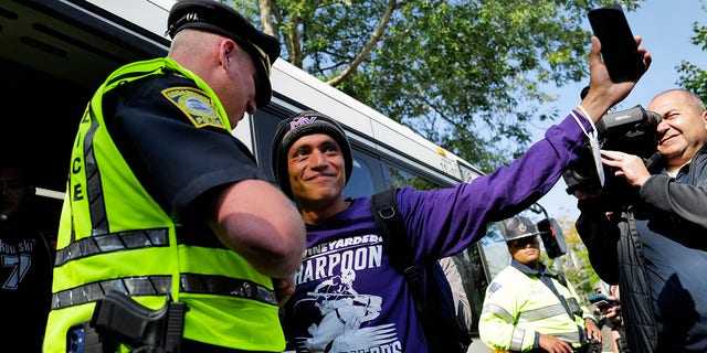 Carlos, a Venezuelan migrant, waves to volunteers before boarding a bus to the Vineyard Haven ferry terminal outside of St. Andrew's Parish House. Two planes of migrants from Venezuela arrived suddenly two days prior causing the local community to mobilize and create a makeshift shelter at the church. 