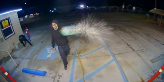 The individuals are seen dousing a business with gasoline early Monday morning in Bakersfield, California.