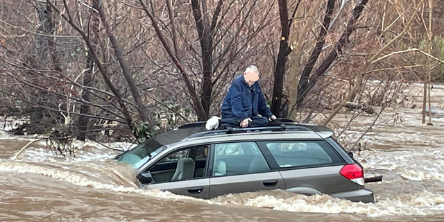 A man in California takes refuge on the roof of his car after getting trapped in floodwaters.