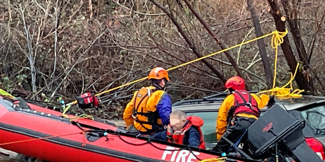 A rescued man makes it onto a raft after getting stuck in floodwaters.