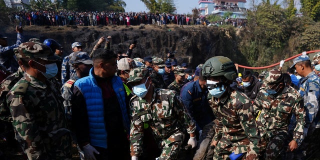 Members of Nepal Army carry the body of the victim of a plane crash at the crash site of an aircraft carrying 72 people in Pokhara in western Nepal January 15, 2023. (REUTERS/Rohit Giri)