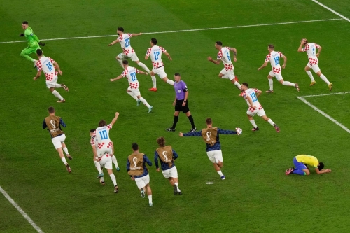 Croatian players run around the field and celebrate their victory as Marquinhos, bottom right, falls to his knees.