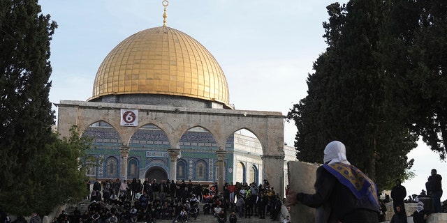 A Palestinian protester takes cover behind a makeshift shield during clashes with Israeli police at the Al-Aqsa Mosque compound in Jerusalem's Old City, Friday, April 22, 2022. Israeli police and Palestinian youths clashed again at a major Jerusalem holy site sacred to Jews and Muslims on Friday despite a temporary halt to Jewish visits to the site, which are seen as a provocation by the Palestinians.