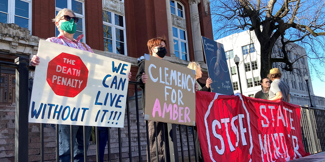 Sue Gibson, left, of Jefferson City, and Jay Castilow, of Columbia, hold signs along with others outside the Missouri Supreme Court building while protesting the execution of Amber McLaughlin on Tuesday, Jan. 3, 2023, in Jefferson City, Mo. McLaughlin was convicted of killing Beverly Guenther in 2003. 