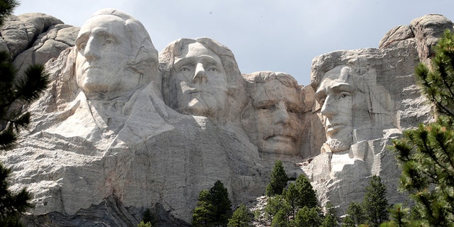 The busts of U.S. presidents George Washington, Thomas Jefferson, Theodore Roosevelt and Abraham Lincoln tower over the Black Hills at Mount Rushmore National Monument.