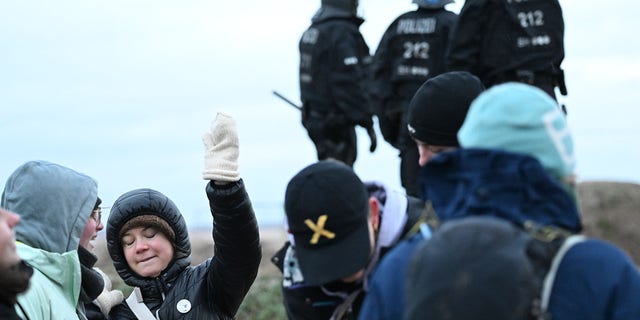 Climate activist Greta Thunberg stands with other activists between Keyenberg and Lützerath under police surveillance at the open pit mine and dances. 